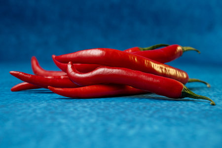 Delicious and nutritious ripe red hot chili peppers on blue background