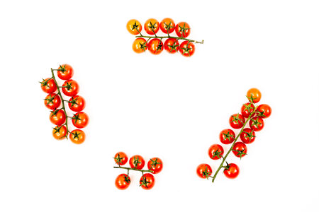 Clusters of ripe red cherry tomatoes viewed from the top on white background