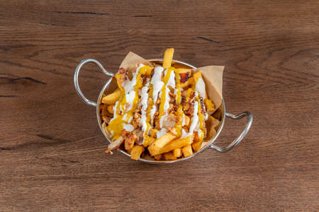 portion of chips with cream cheese cheddar sauce and fried bacon and chicken chunksの写真素材