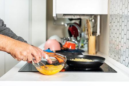 Man's hands beating eggs to cook a Spanish potato omelette