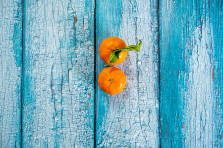 Two ripe tangerines viewed from the top on wooden blue plank table with peeling paintの写真素材