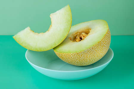 Half yellow melon with seeds and a cut and clean portion of seeds on a blue deep plateの写真素材