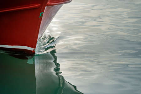 Red hull of a ship and its reflection plowing through the waters of the Black Seaの写真素材