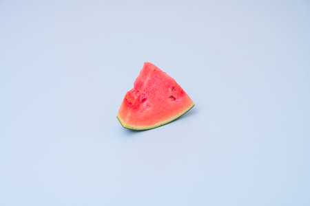 Triangular portion of fresh seedless watermelon on light blue tableの写真素材