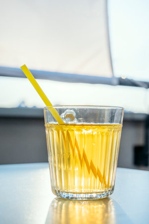 Glass of pineapple juice with straw on terrace table at sunsetの写真素材