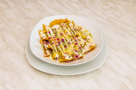 Green chilaquiles with tortilla chips, grated cheese and red onion and cheese syrup