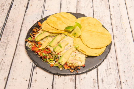 Combined Mexican dish of beef wire with slices of avocado, sautÃ©ed vegetables, small corn...