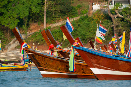 Bows of cheerful and colorful long tail boats moored on a Thai beachの写真素材
