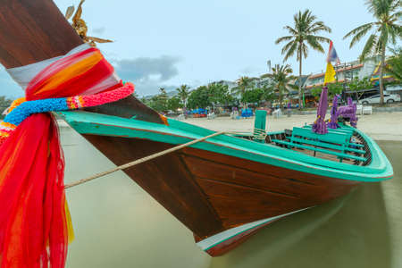 Beautiful long tail boat painted with bright colors moored on the beachの写真素材