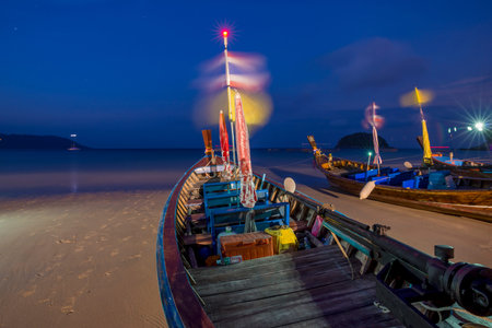 Long exposure image of wooden long tail boats beached on the sand at nightの写真素材