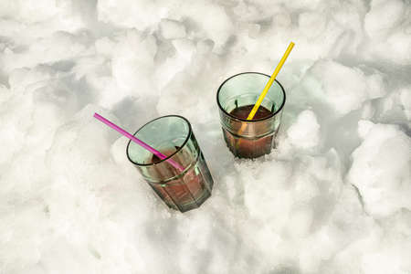 Soda glasses with straws chilling in the snowの写真素材