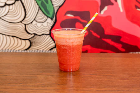 Strawberry juice slush in a plastic cup and yellow strawの写真素材