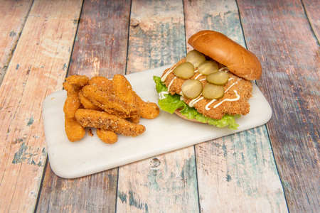 Crispy chicken burger with pickles, mayonnaise and lettuce with battered mozzarella cheese fingersの写真素材