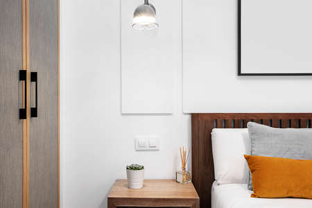 Detail of wooden headboard with cushions, bedside table and closet doors in a holiday rental apartmentの写真素材