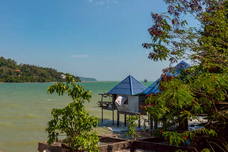 Slightly rickety stilt bungalows with blue pyramid roofs on the Phuket coast facing the Andaman Sea on a summer day.の写真素材