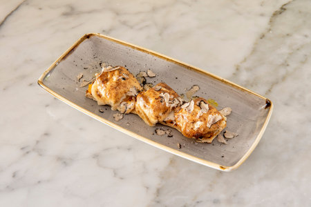 Ravioli stuffed with meat with olive oil topped with slices of white truffle on a white marble tableの写真素材