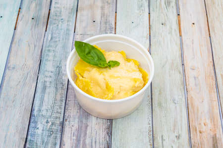 Ravioli filled with four cheese sauce and grated cheese with basil inside a take away containerの写真素材