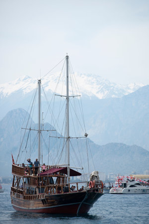 Tourist pleasure boats on the Mediterranean coast of Antalya with high snowy mountains in the...