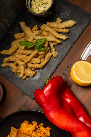 Spanish food dishes served as tapas in restaurant. Paella, squid rabas in batter and fried in olive...