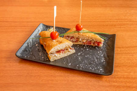 Ham bikini sandwich with truffled tomatoes with grated parmesan cheese on cherry tableの写真素材