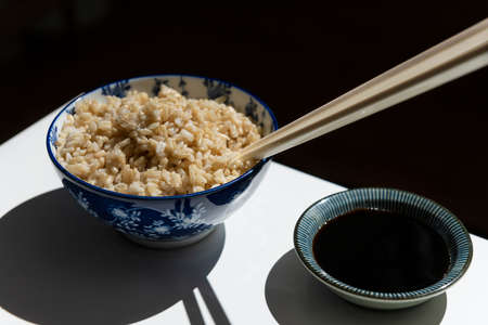 Blue and White Chinese Porcelain Flower Bowl Filled with Rice with White Chopsticks and Soy Sauceの写真素材