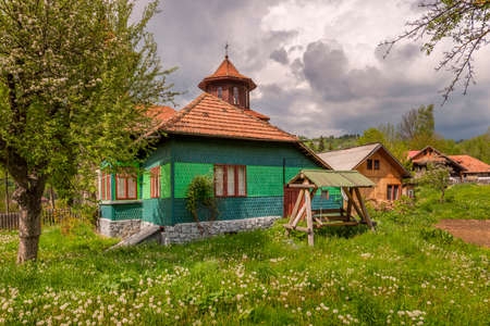 Vintage polychrome wood and stone country house with beautiful garden full of grass and flowers in the middle of the Carpathian Mountainsのeditorial素材