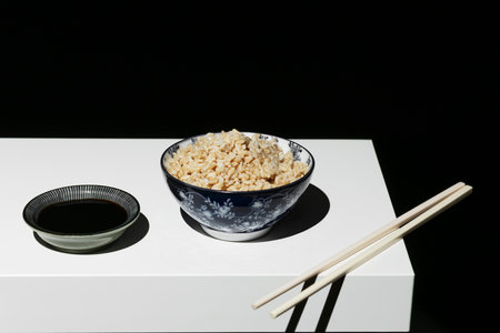 Bowl of white rice with chopsticks with soy sauce on the white shelfの写真素材