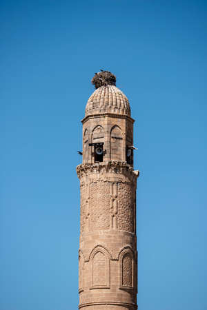 Ancient sandstone minaret with loudspeakers and storks nest on topの写真素材