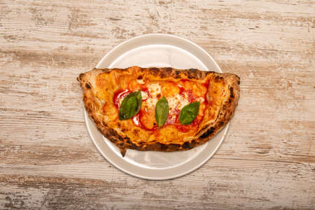 classic Italian calzone stuffed with cheese and ham cooked with tomato and basil cooked in a traditional stone ovenの写真素材