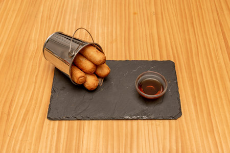 serving of traditional Venezuelan tequeÃ±os filled with fresh cheese with cane sugar syrup for...