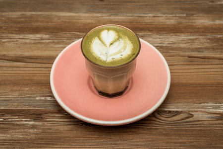 Coffee with milk and matcha with drawing of barista with milk cream on pink plateの写真素材