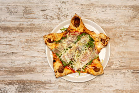 Star-shaped crust pizza with prosciutto, tomato and mozzarella cheese, minced meat and grated Parmesan cheeseの写真素材