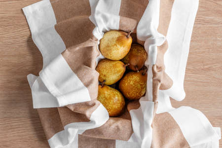 Conference pears inside a container covered by a white and light brown dishclothの写真素材