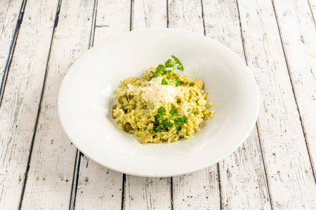 risotto with asparagus, mushrooms and parsley topped with grated cheese on a deep white plateの写真素材