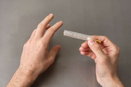 Hands rolling a cigarette laughing with thin rice paperの写真素材