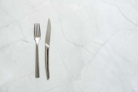 Stainless steel fork and knife on white marble tableの写真素材