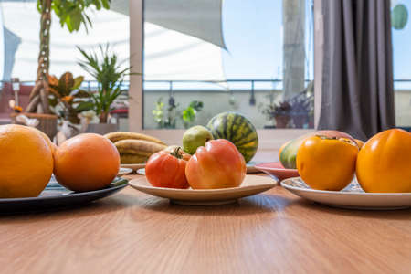 Set of dishes with assorted fruits, tomatoes and persimmonsの写真素材