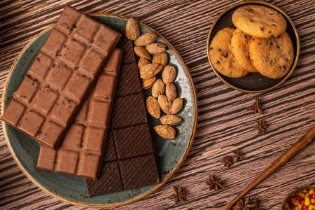 Chocolate bars with almonds, star anise and chocolate cookies and blue plateの写真素材