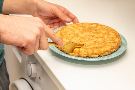 Chopped potato omelette with golden covered on blue plate and white kitchen counterの写真素材