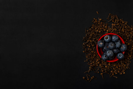 Blueberries and cloves on black background