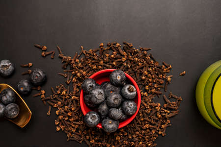 Ripe blueberries and clove spices on black backgroundの写真素材
