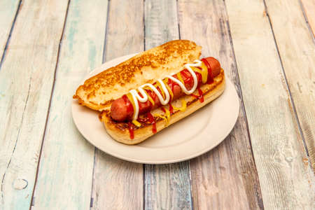 Classic hot dog with mustard, ketchup and mayonnaise on toasted brioche breadの写真素材