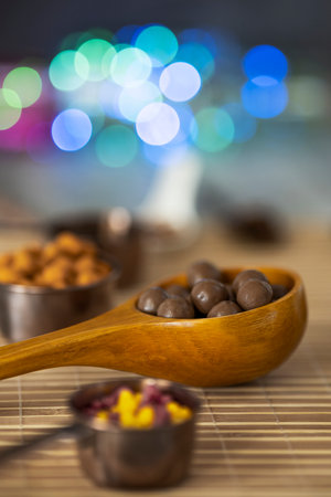 Still life with chocolates, nuts and decorative colored lightsの写真素材