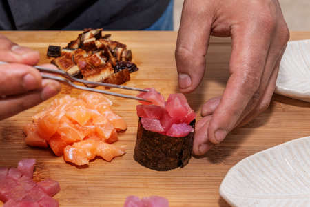 Chef's hands filling gunkan with red tuna and Norwegian salmon and nori seaweedの写真素材