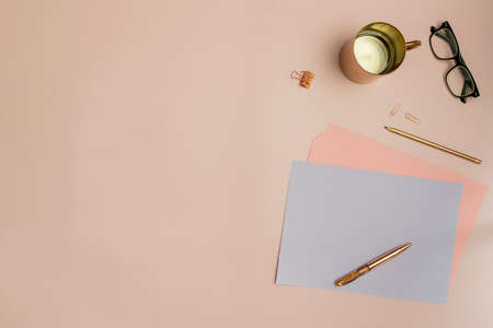 Still life in pastel pink tones with papers, red gold pens and pencils and reading glassesの写真素材
