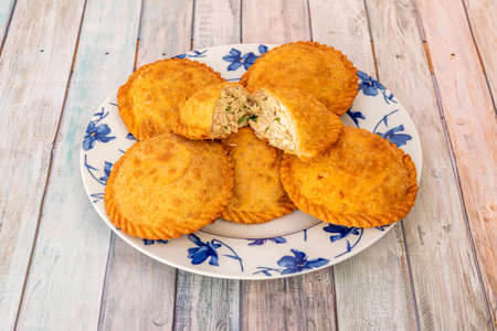 Empanadas stuffed with pulled chicken meat with parsley on white plate and blue flowersの写真素材