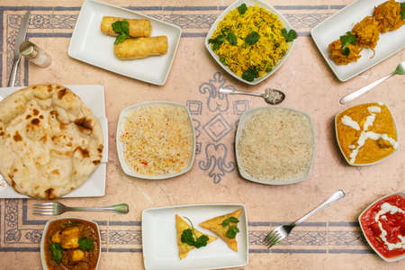 Set of Indian food dishes with various flavors curry, garlic naan, and basmati rice with cheese rollの写真素材