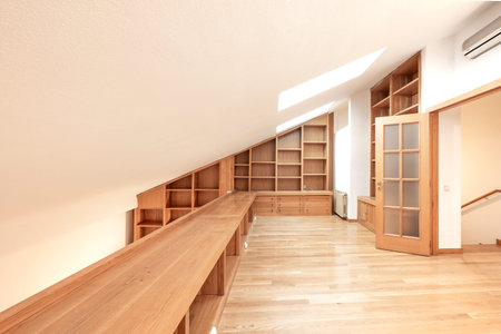 Room with sloping ceiling and oak wood bookcase with parquet floorsの写真素材