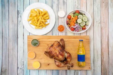 Roast chicken menu with homemade chips, vegetable and tomato salad and various sauces and chili with yellow Ecuadorian drinkの写真素材
