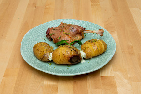 Duck leg cooked in the oven with potato garnish and garlic sauceの写真素材